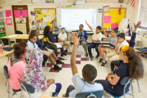 Students raise their hands to share what they noticed during the Interactive Modeling.