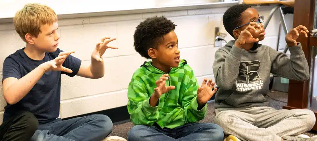 Three students sitting on the floor of a classroom engaged in an activity