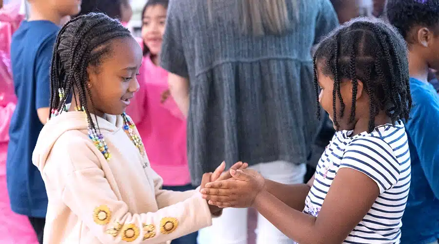 Two girls smiling and interacting during a Responsive Classroom Energizer activity