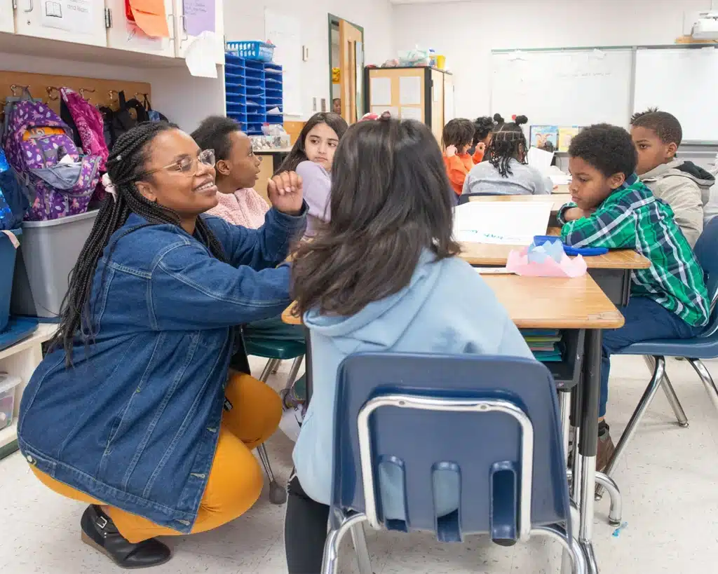 A teachers works with a group of students at their table. Responsive Classroom supports MTSS.