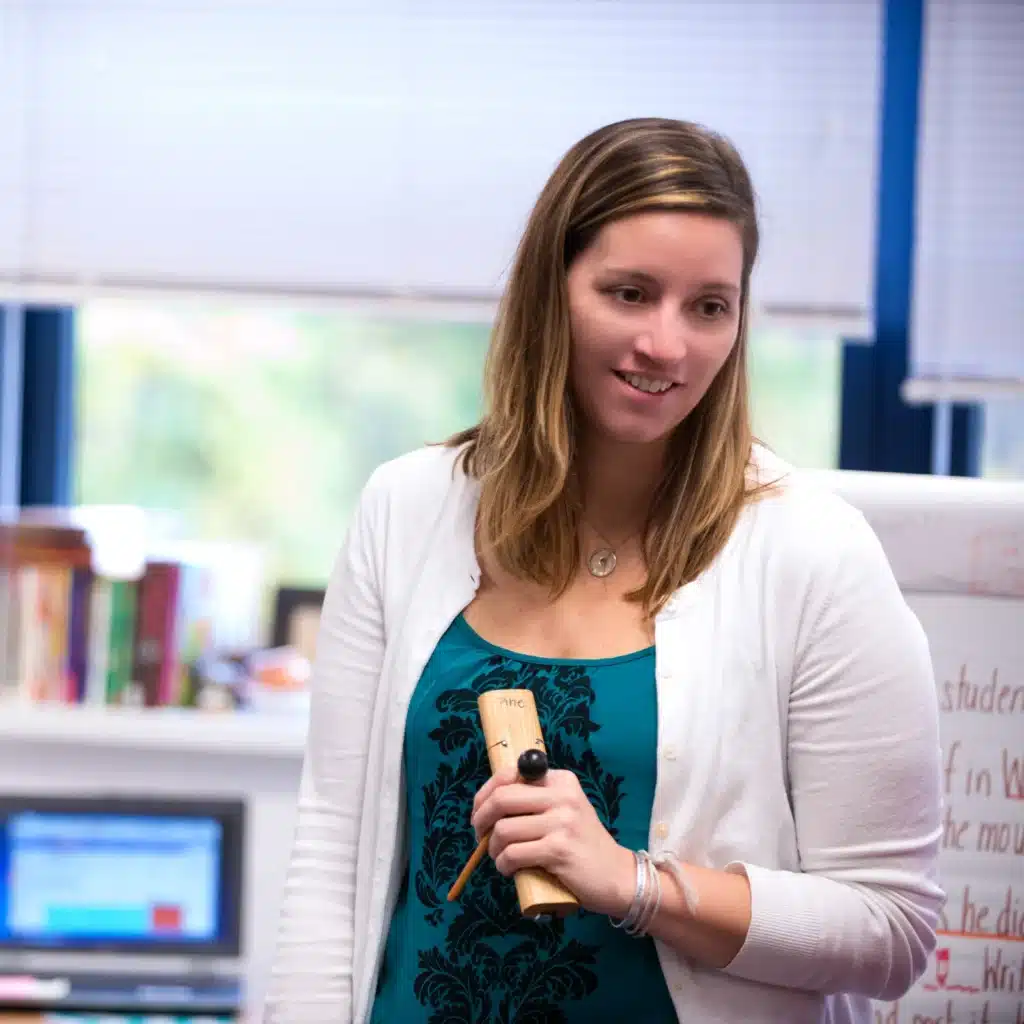 A smiling teacher holding the Responsive Classroom signal chime